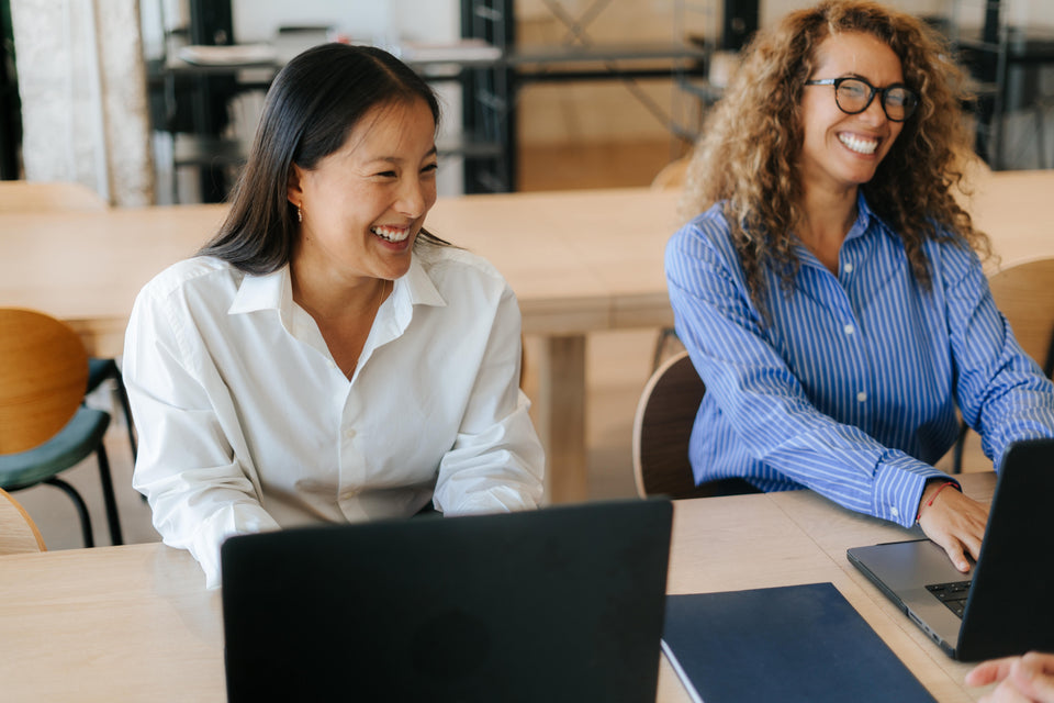 Two people working in front of a laptop and smiling